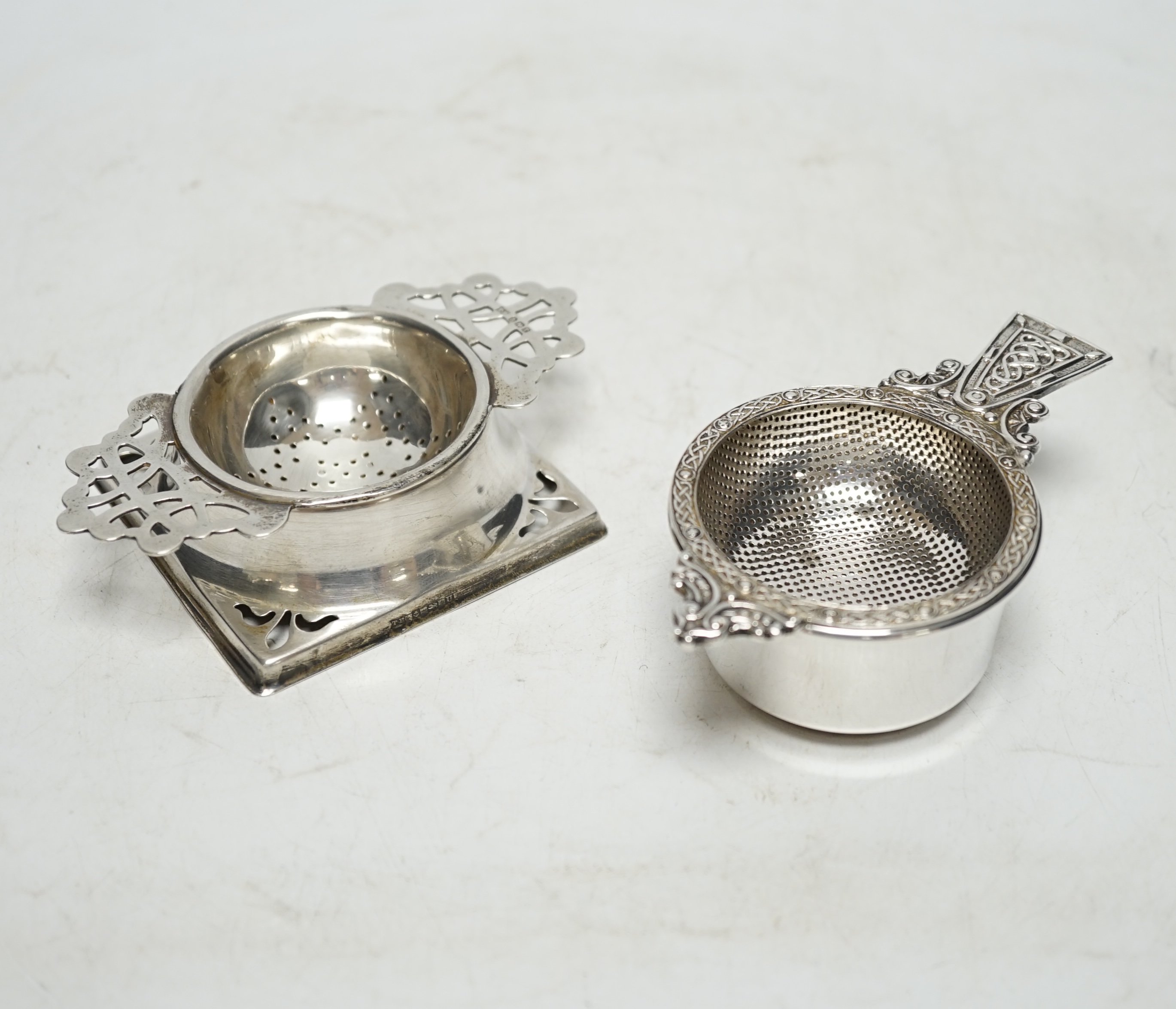 An Elizabeth II silver tea strainer and stand, with Celtic decoration, by Mappin & Webb, Sheffield, 1962, 10.7cm and one other silver tea strainer on stand. Condition - fair